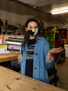 A photo of Tessa wearing a denim shirt holding a pasta machine!